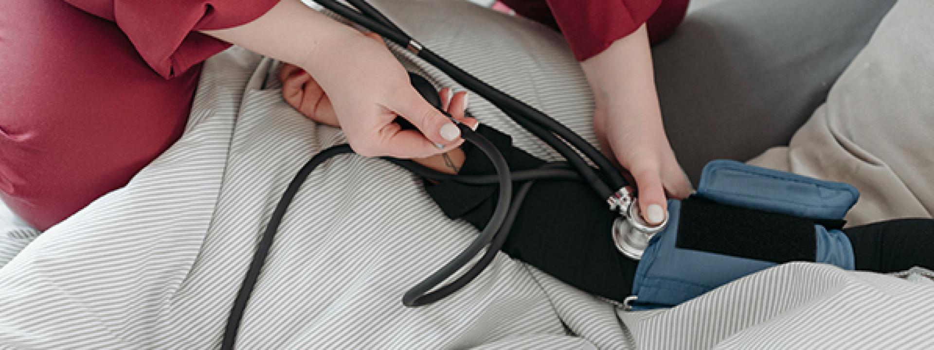 female technician taking blood pressure of patient