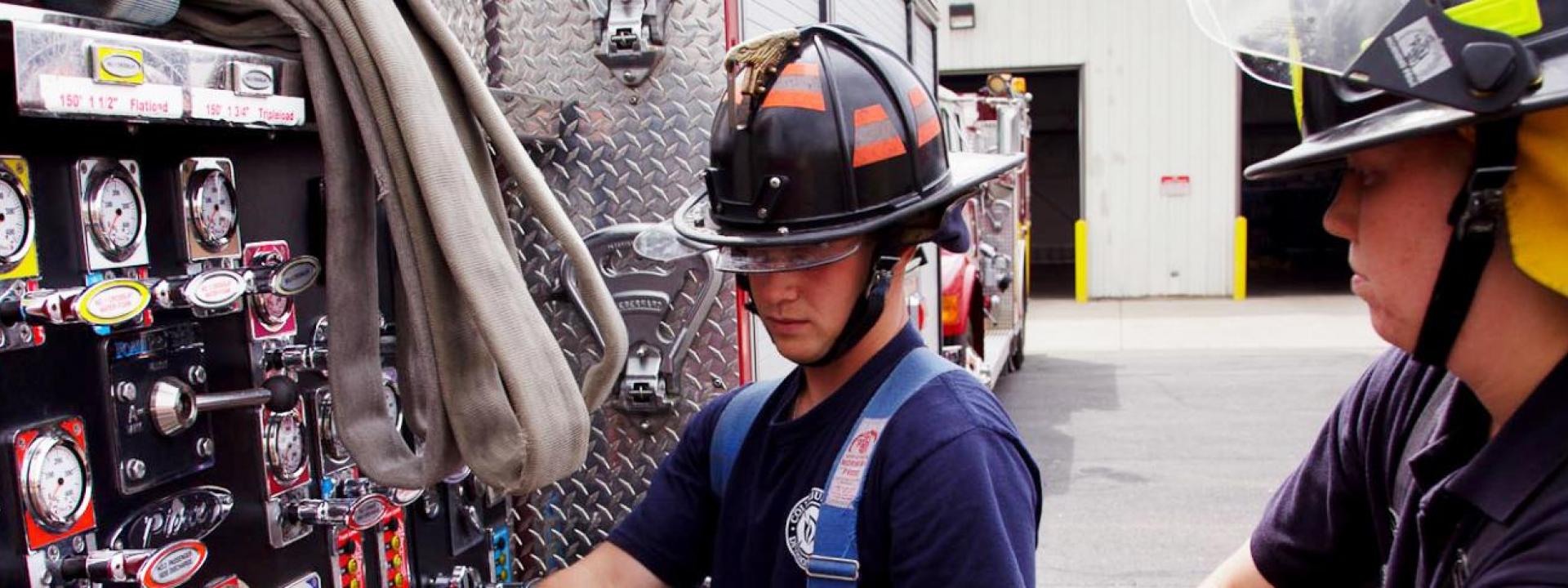 2 fire fighters working on fire truck controls