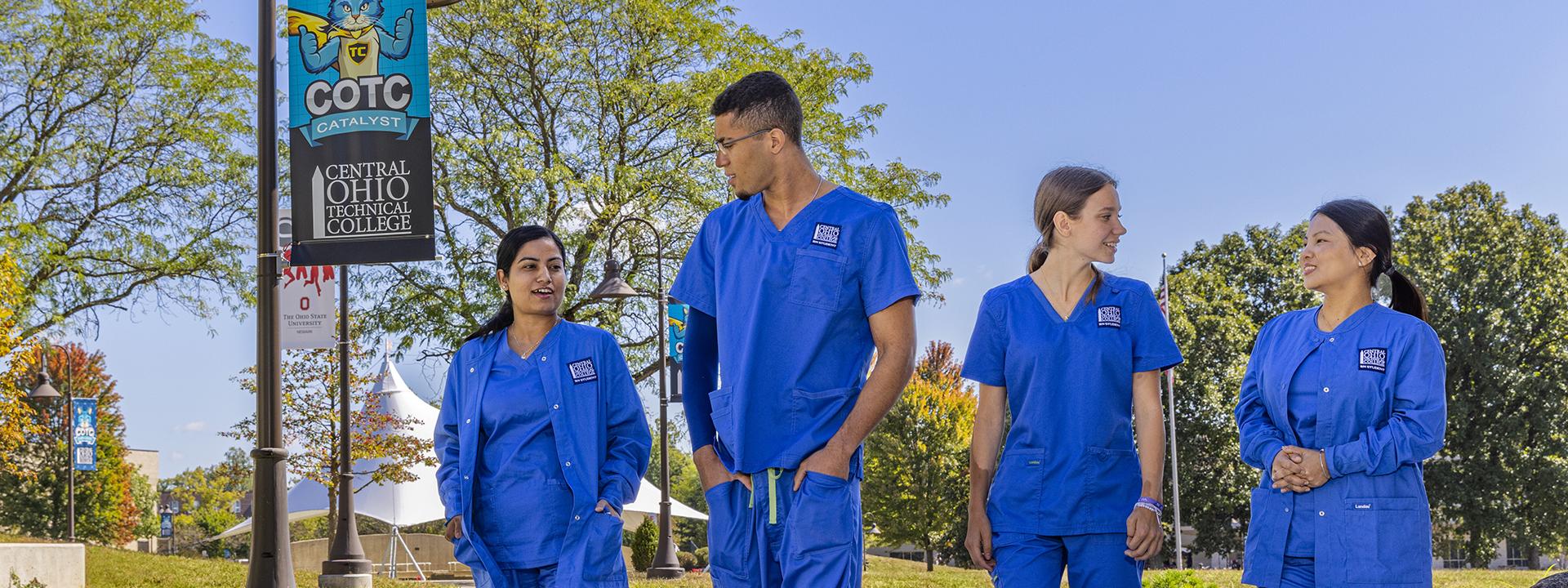 Four students in medical scrubs walk at the COTC campus in Newark.