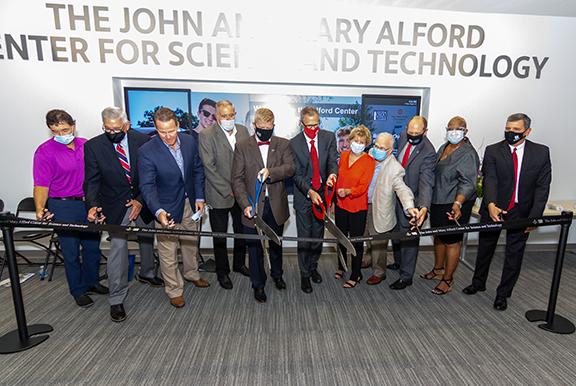 Dignitaries lined up in front of ribbon with scissors preparing to cut