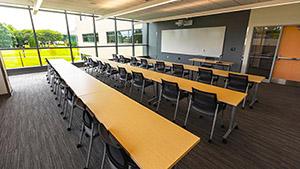 Classroom with long tables, chairs facing whiteboard