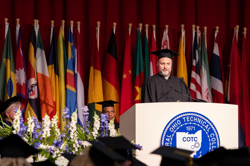 Ruben Clark dressed in academic regalia speaks to graduates from a podium at commencement.