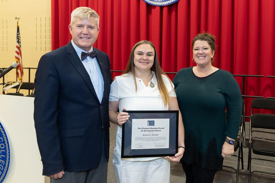 Barnhart Award recipient Brenda Woodby holds a plaque while standing next to COTC President John Berry at the autumn semester nurses pinning ceremony. 