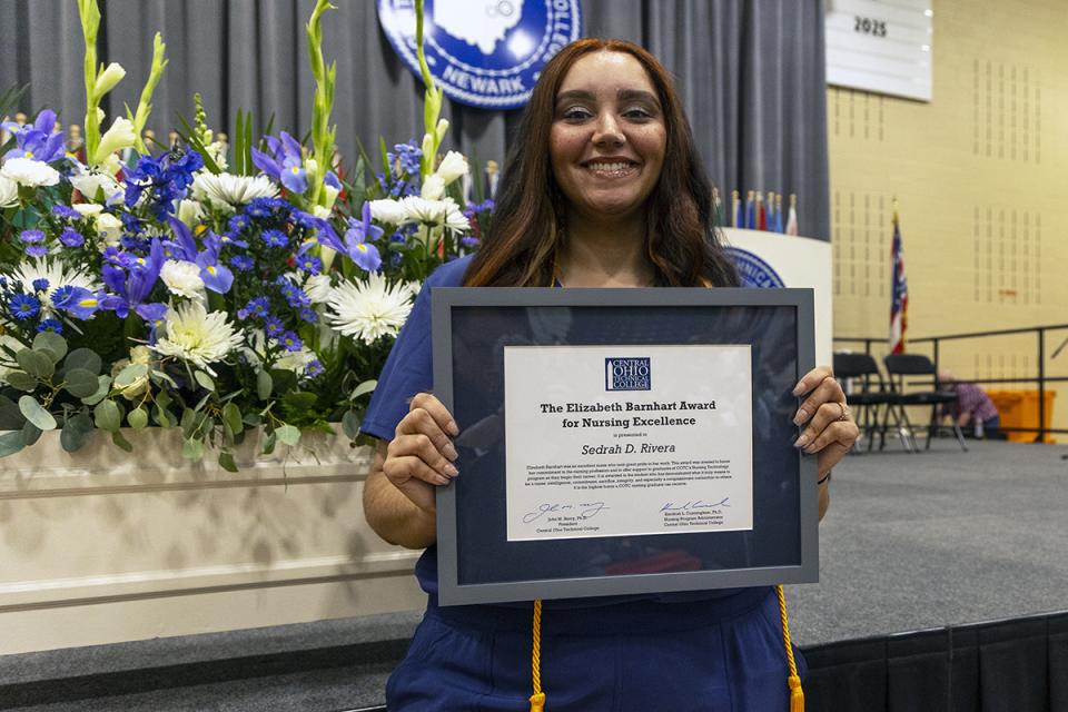 Sedrah D. Rivera holds her framed award certificate at the nursing pinning ceremony.