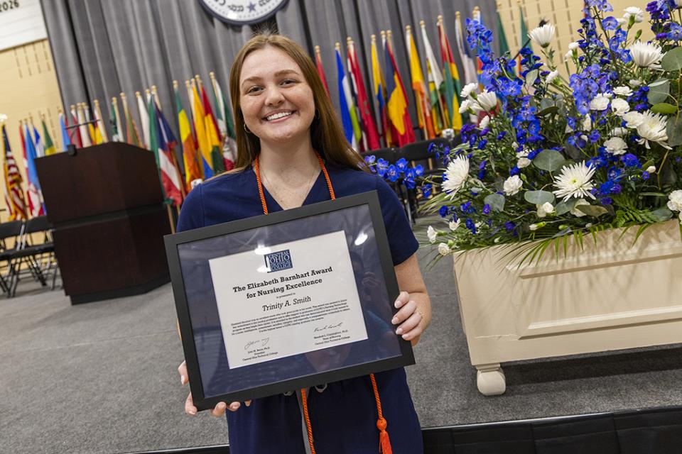 Trinity Smith holds a framed certificate announcing her receipt of the Barnhart Award for nurses at the Nursing Pinning Ceremony.