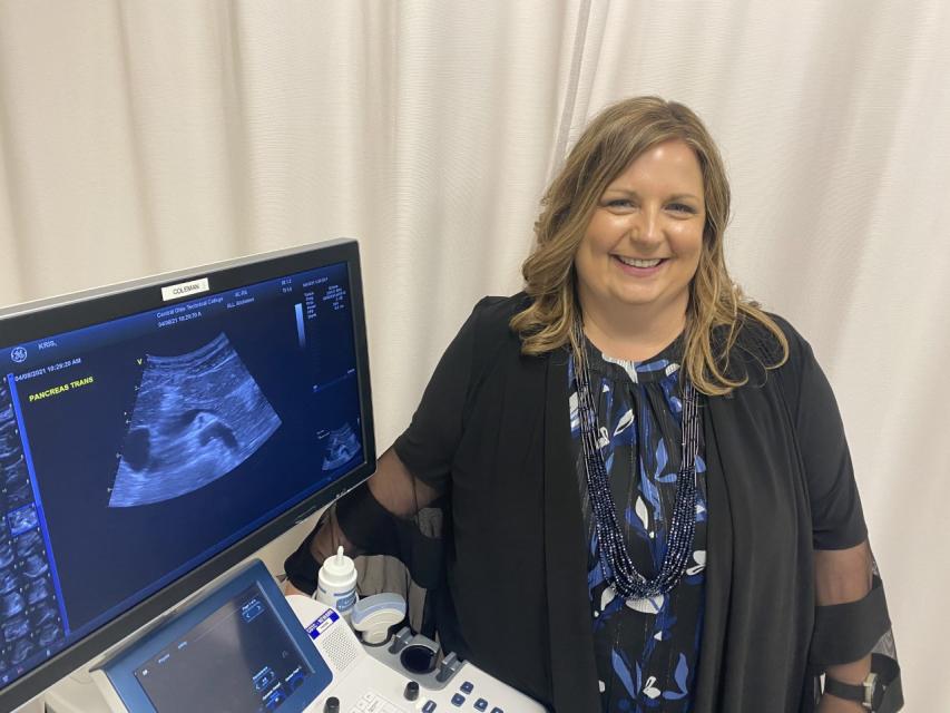 Beth Eyster stands next to an ultrasound machine. 