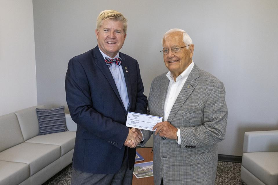 Robert McGaughy  shakes hands with 'COTC President John Berry as he hands him a check. 