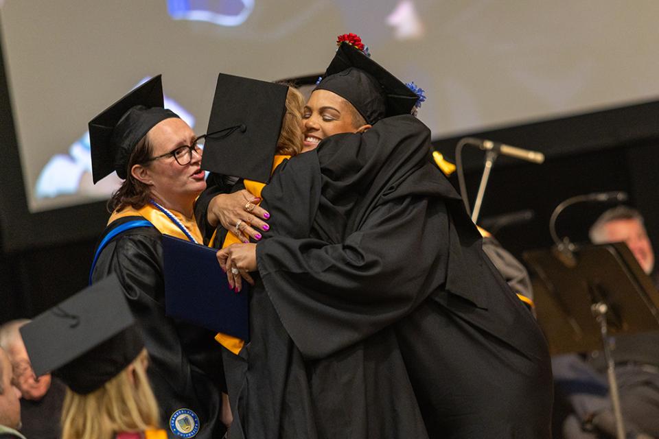 Two graduates embrace each other in a hug during the commencement ceremony.