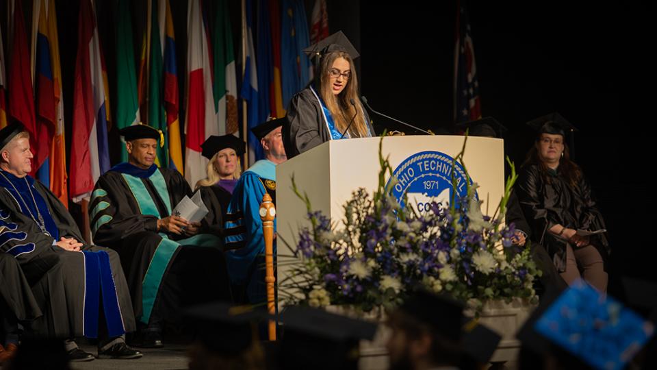 Graduate and speaker Jessica Kinser stands at the podium giving her speech.