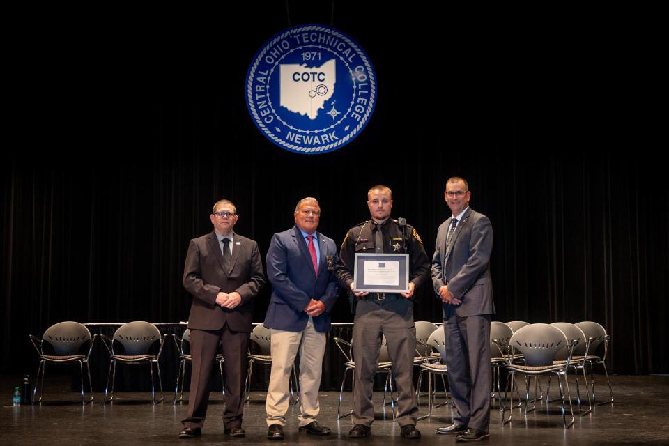 Commander James Rease, Logan Trombley, Sheriff Randy Thorp, and Representative Kevin Miller. Logan Trombley stands on stage holding his award certificate with Commander James Rease, Sheriff Randy Thorp, and Representative Kevin Miller.