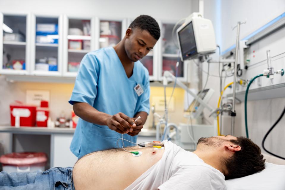 A healthcare employee places electrodes on a patient's chest to perform an EKG.