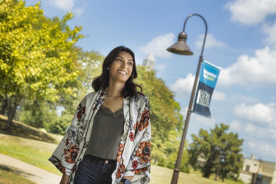 A student on campus looks into the distance and smiles.