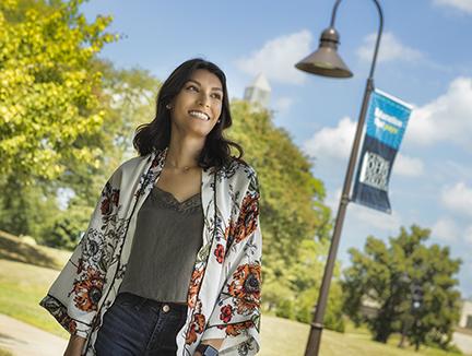 Female student outside on campus with street light and cotc banner on pole, blue skies