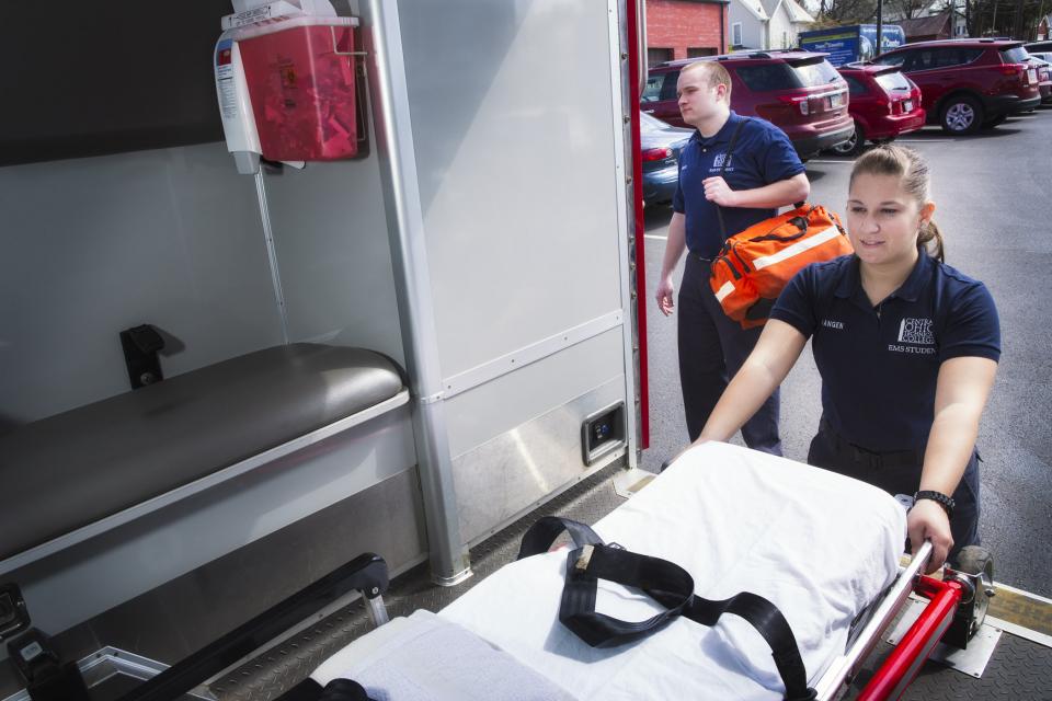 Student taking gurney out of the back of ambulance