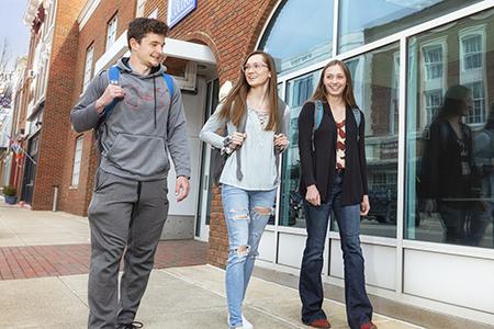 One male and two female students walk outside of Ariel Hall on the Knox campus.