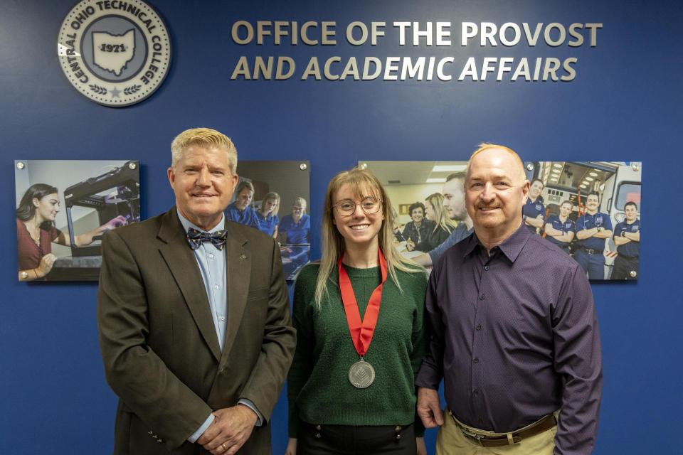 Cassie Summer wears her League Excellence Award medal while standing between COTC Provost Gregory Ferenchak and COTC President John Berry.