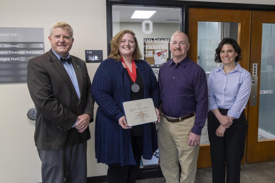 Rachel Brandenburg holds her League Excellence Award certificate while standing between COTC Provost Gregory Ferenchak, COTC President John Berry and Director of Marketing and Public Relations Ashton Lahman.