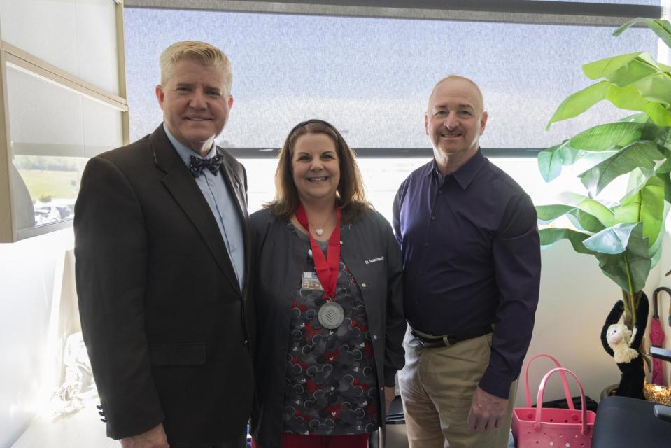 Susan Cooperider wears her League Excellence Award medal while standing between COTC Provost Gregory Ferenchak and COTC President John Berry.