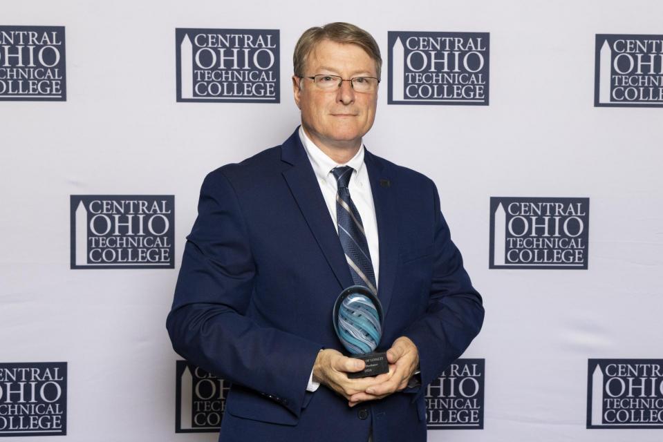 Portrait of Brian Boehmer holding his Legends of Loyalty award. 