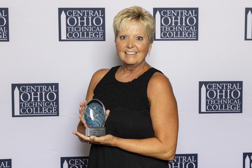 Portrait of Jan Tomlinson holding her Legends of Loyalty award. 