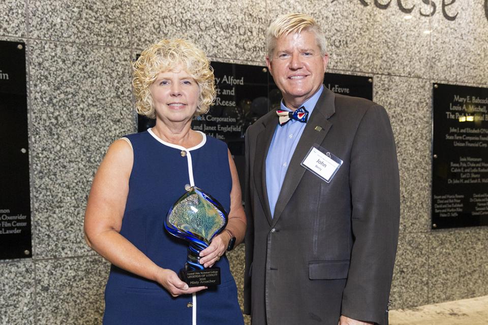 Misty Amacher stands next to COTC President John Berry holding the Legends of Loyalty award.