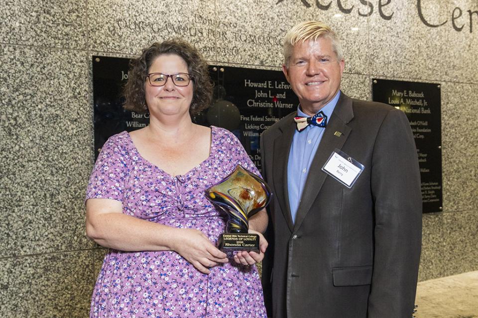 Rhonda Carter stands next to COTC President John Berry holding the Legends of Loyalty award.
