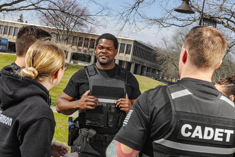 A police officer basic training cadet stands among peers in conversation on the campus. 