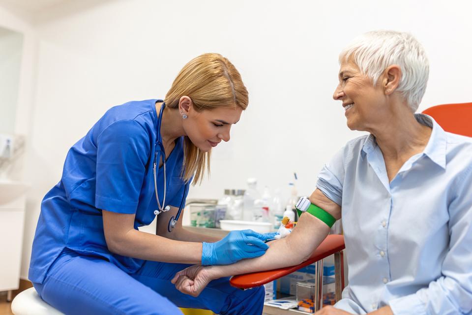 A phlebotomist inserts a needle into a patient's arm. 