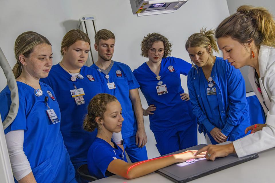 An instructor surrounded by students demonstrates how to do an xray.