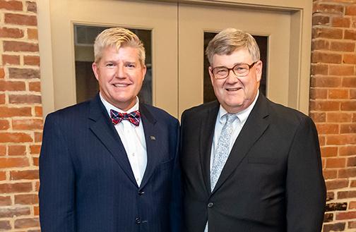 President Berry and Mark Ramser (with glasses) in suits and ties standing in front of a doorway