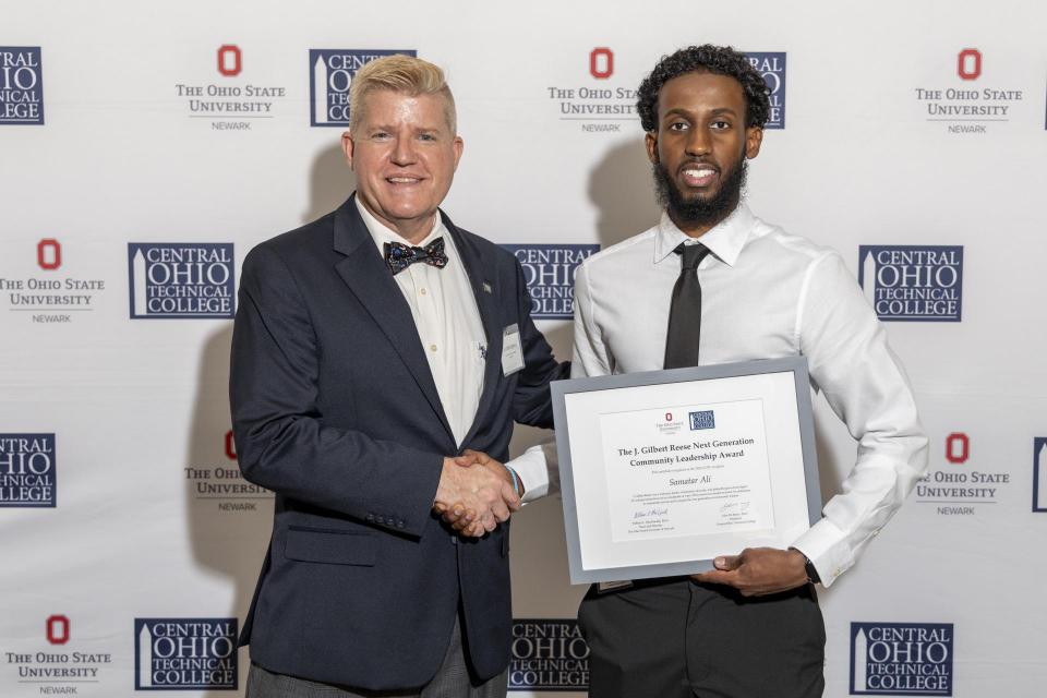 Samatar Ali shakes hands with COTC President John Berry while holding his certificate for the J. Gilbert Reese Next Generation Community Leadership Award .