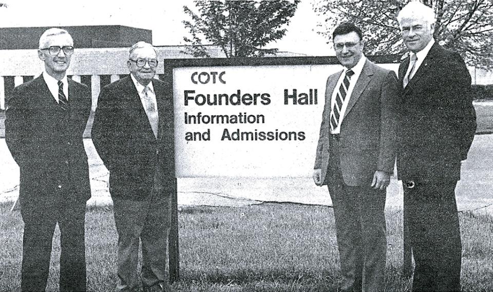 Early leaders of the Newark campus' Gilbert "Gib" Reese, Howard LeFevre, Barnes and Julius Greenstein stand next to the Founders Hall sign on campus in a historical black and white photo. 