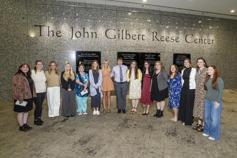 Fifteen students who received a scholarship from the Reese family stand in the J. Gilbert Reese Center.