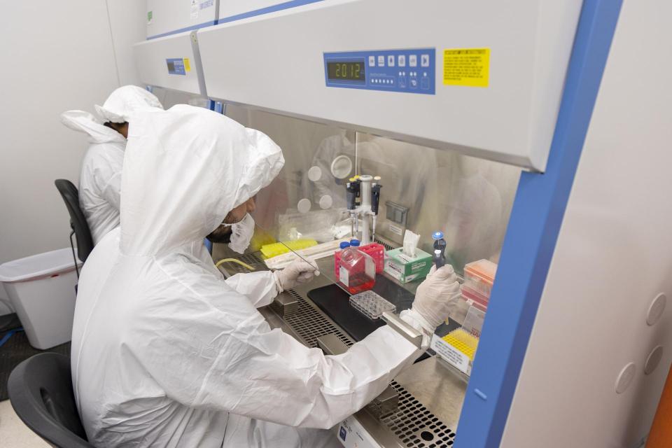 Students interact with laboratory equipment in cleanroom.