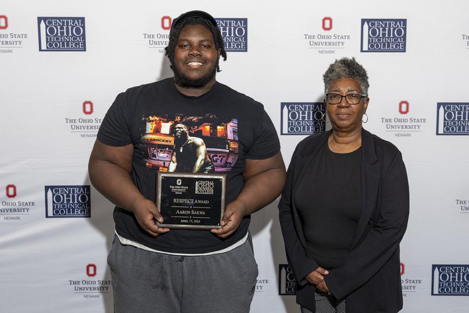Aaron Sakwa holds a plaque for receiving the RESPECT Award and  stands next to staff member Vorley Taylor who nominated him for the award.