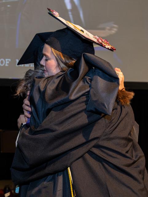 Lora Smith and Lyida Fink embrace each other with a hug at COTC's commencement ceremony in December 2022.