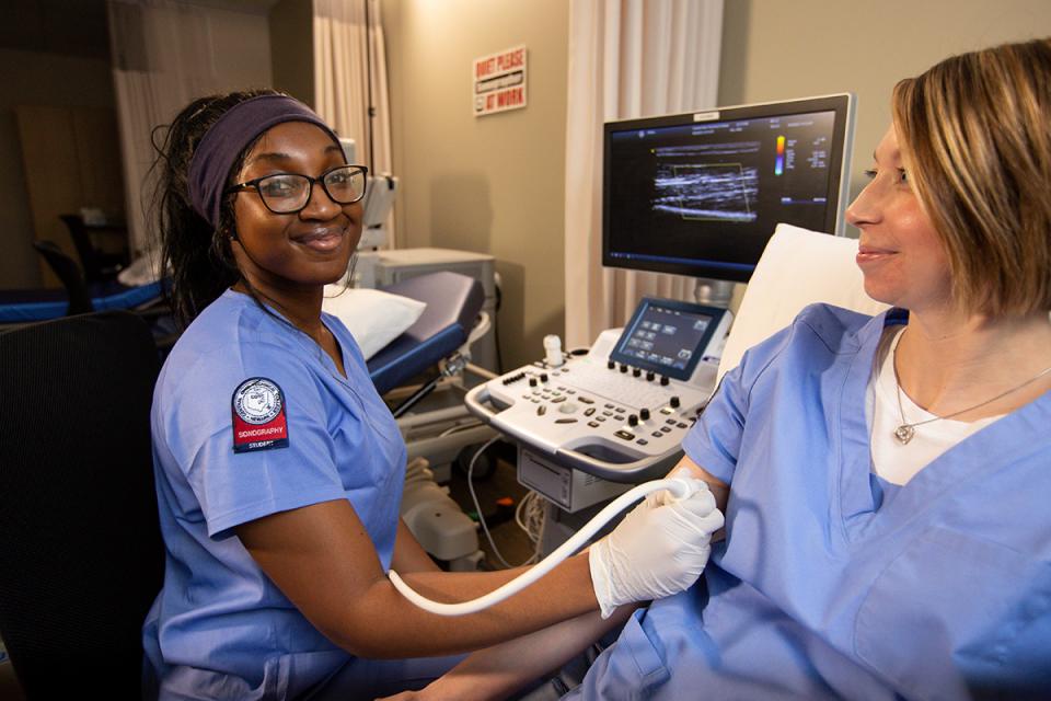 An African American female student practices using ultrasound equipment during sonography lab.