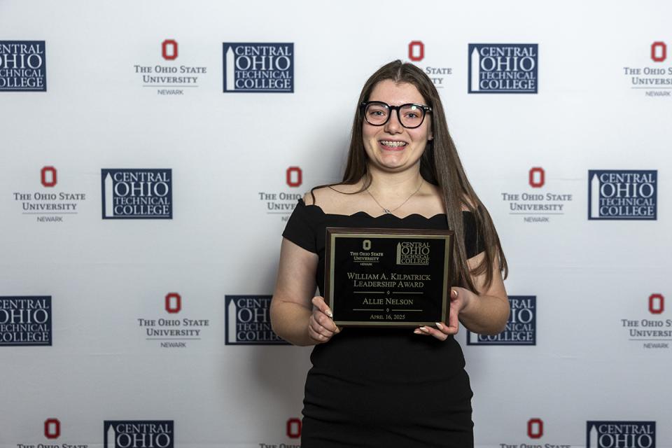 Portrait of Allie Nelson holding their award plaque.