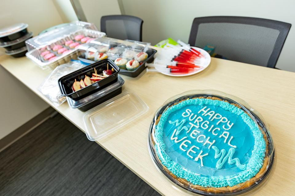 Students prepared medical themed food, including jello-filled syringes, apple slices mouths with marshmallow teeth, and a frosted cookie that says "happy surgical tech week."