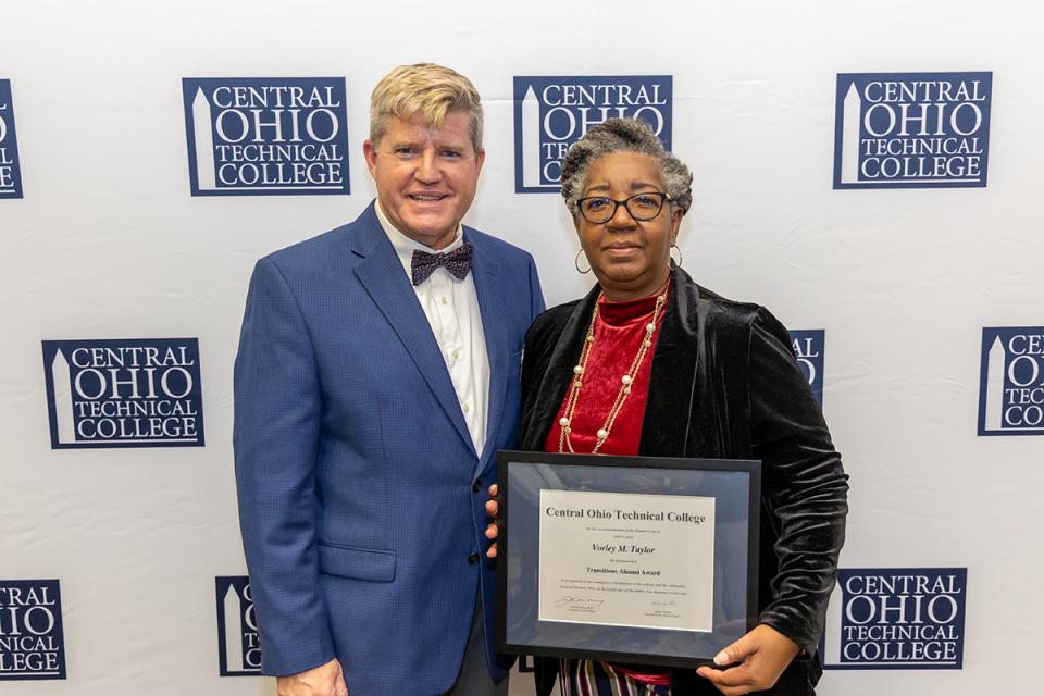Vorley Taylor stands with COTC President John Berry holding her framed award certificate.
