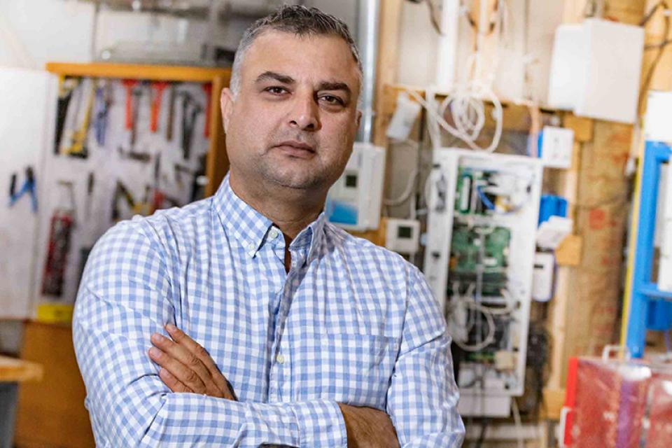 Asif Khan stands in front of engineering equipment in a classroom