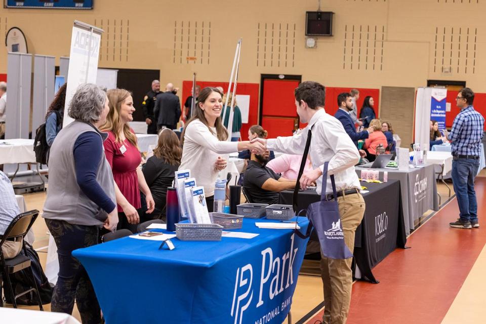 An employer shakes hands with a student at the career fair.