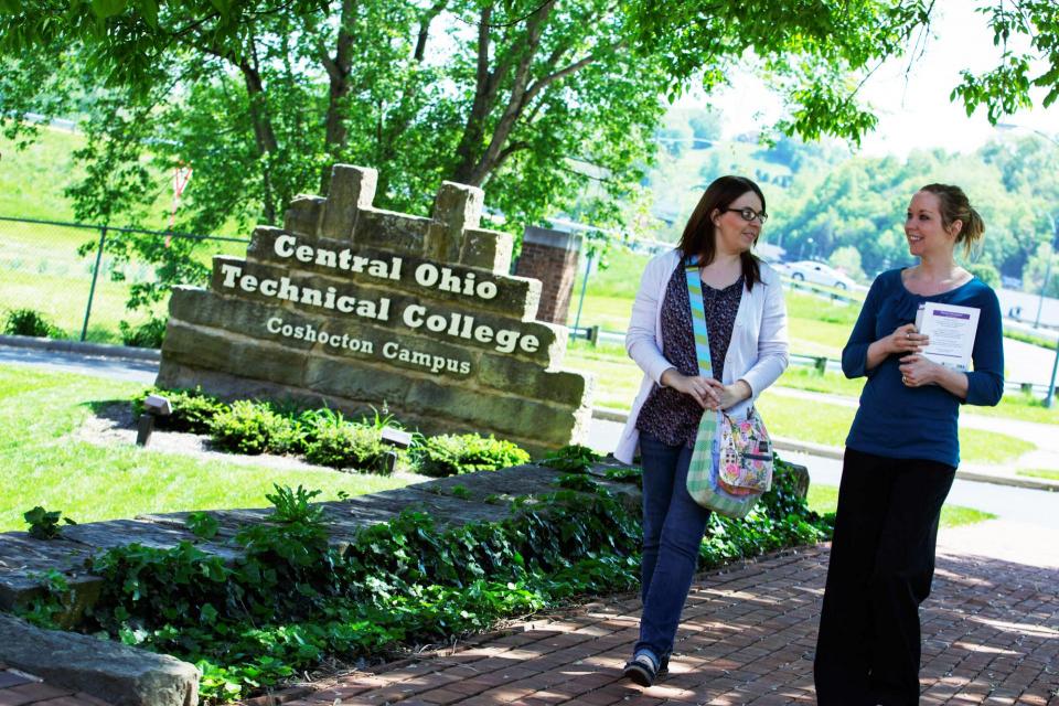 2 girls walking outside Coshocton campus building
