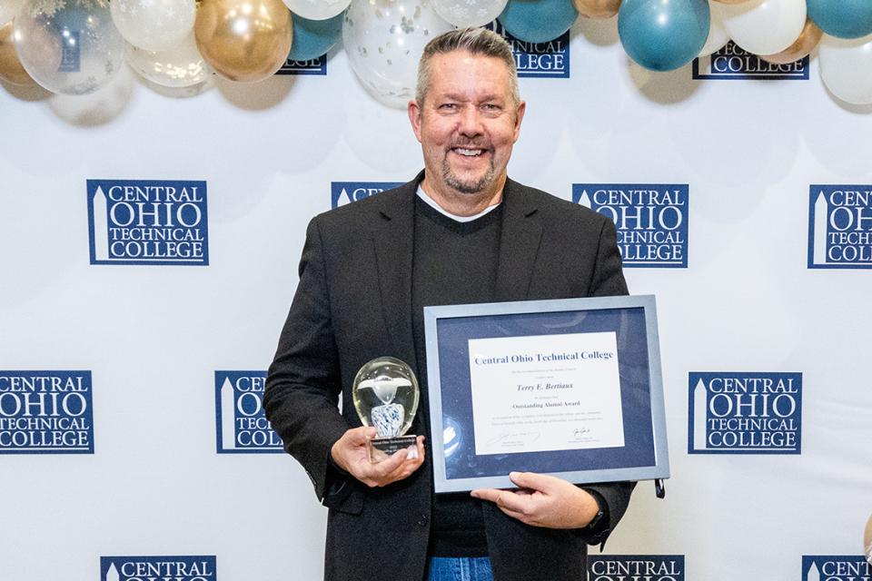 Terry Bertiaux Terry Bertiaux holds his Outstanding Alumni Award certificate and glass trophy.
