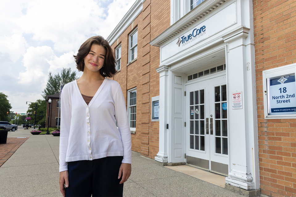 COTC alumna Sophia Tosi stands outside TrueCore Federal Credit Union where she works.