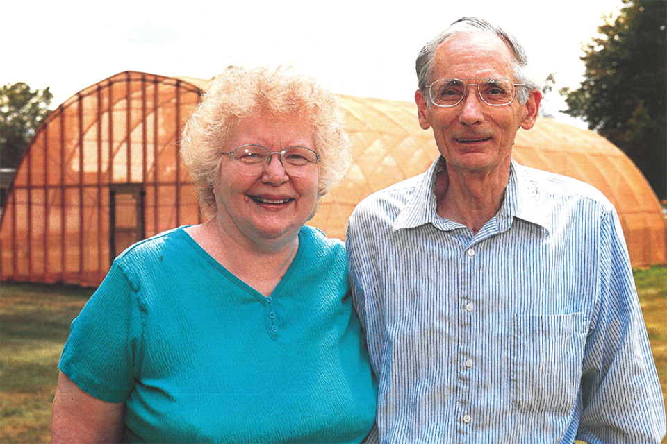 Portrait of Mary Ellen and Lee St. John outside of a greenhouse.