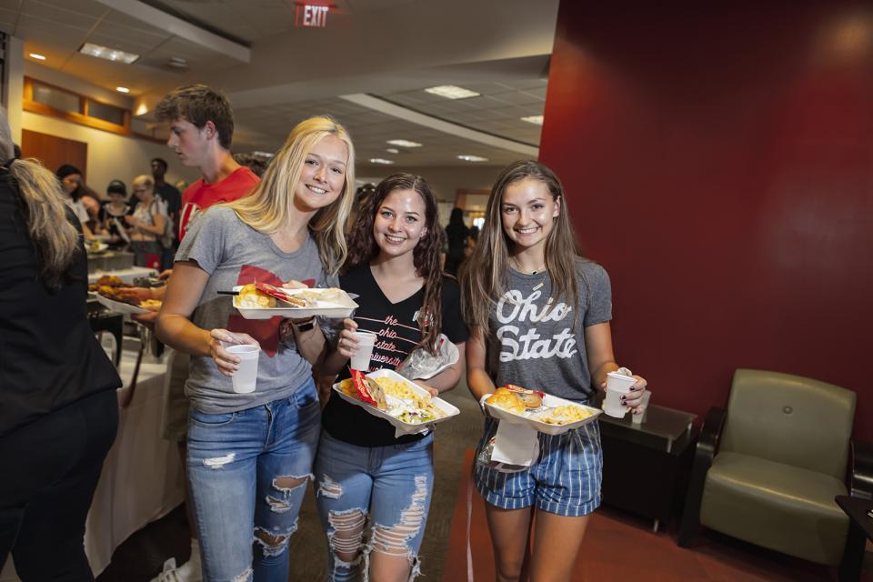Three students hold trays of food from the campus cafeteria. 