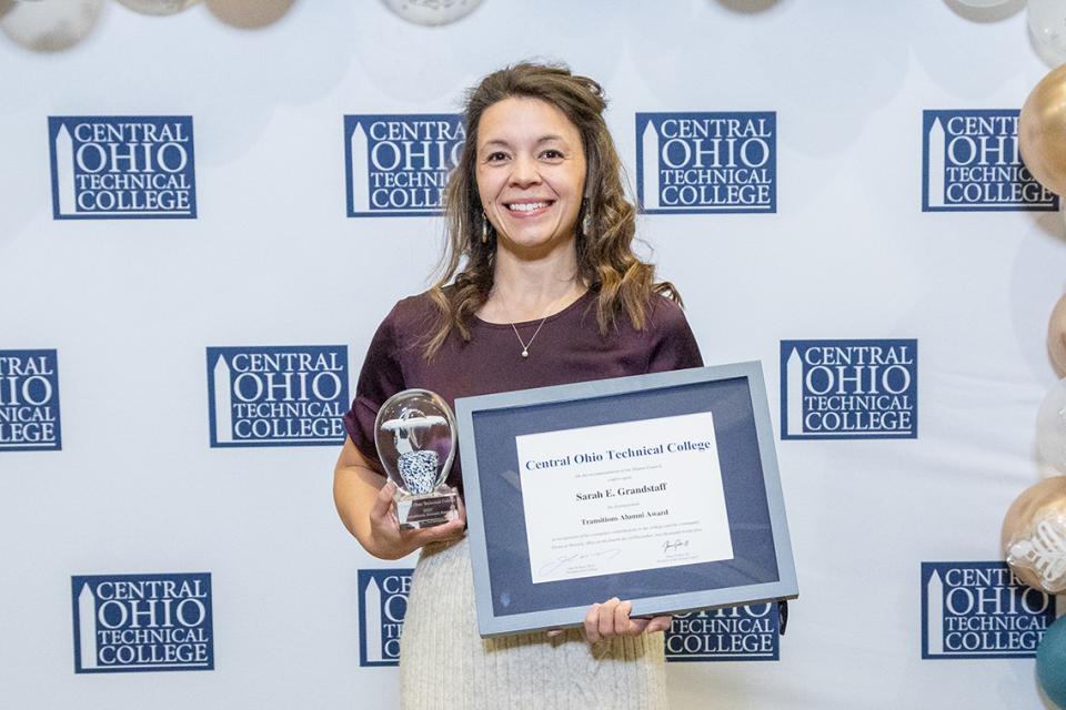 Sarah Grandstaff holds her Transitions Alumni Award certificate and glass trophy.