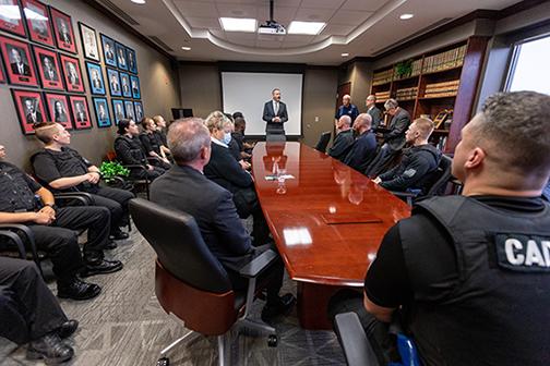 Standing man addressing seated cadets around table in conference room