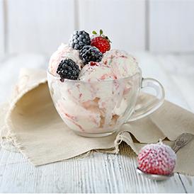 Three scoops of berry rumble ice cream with berries on top in a glass cup